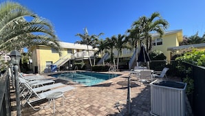 A pool area with lounge chairs, a pool, and a staircase leading to a building. - Spacious one-bedroom beach apartment on Singer Island (Palm Beach Shores)