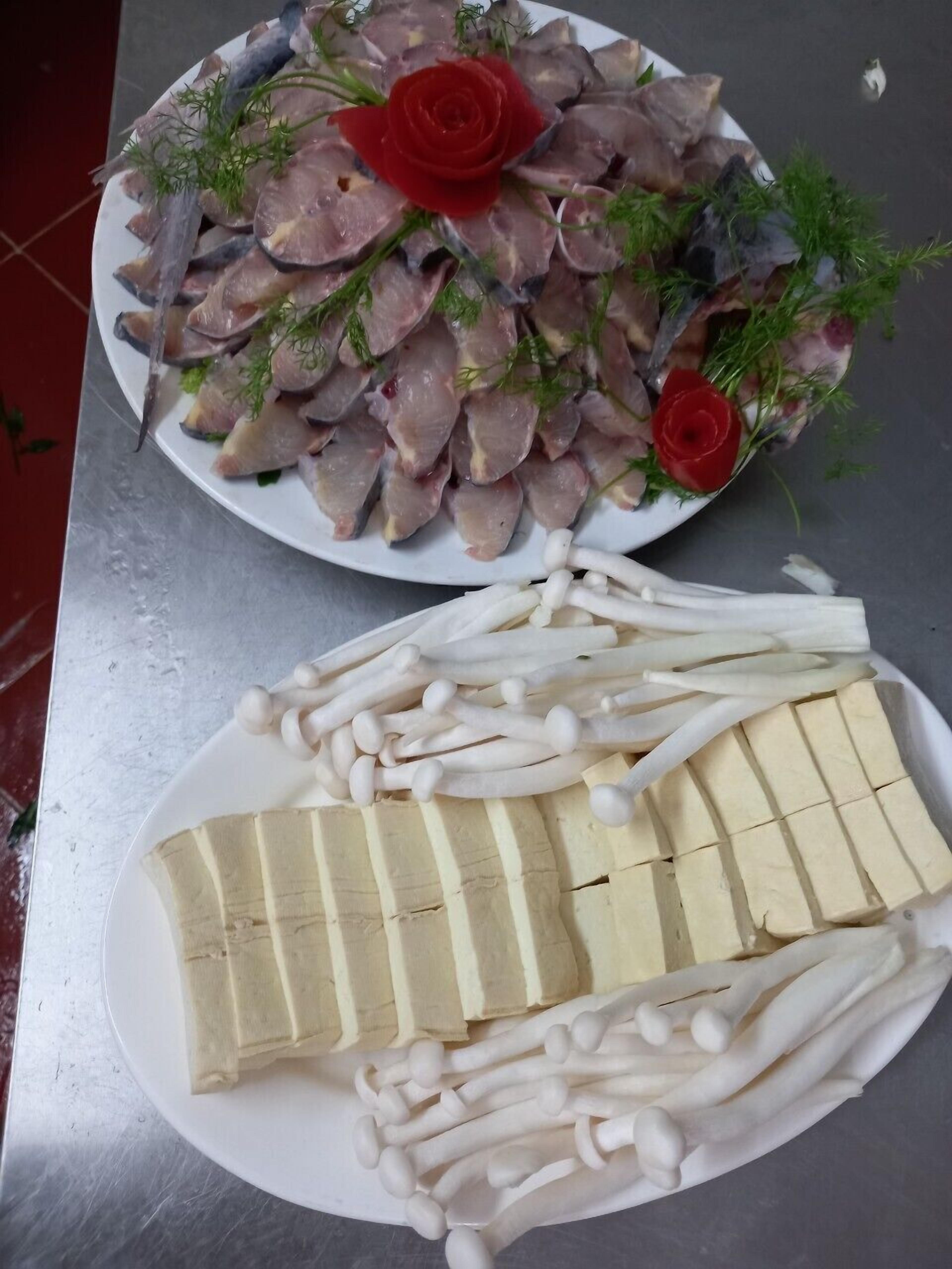 A plate of sliced fish garnished with red roses and dill, and another plate with sliced tofu and mushrooms.