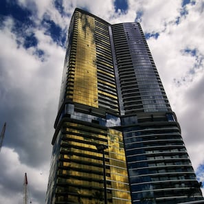 Standing tall with a sleek, modern design, this high-rise building features a striking combination of glass and dark panels.