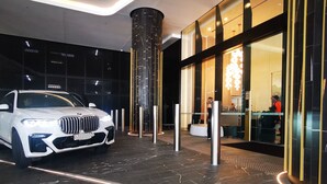 A white car parked in a modern lobby with a glass entrance and a large pillar. - Luxurious 1 Bdrm Apartment in GC Casino (Broadbeach)