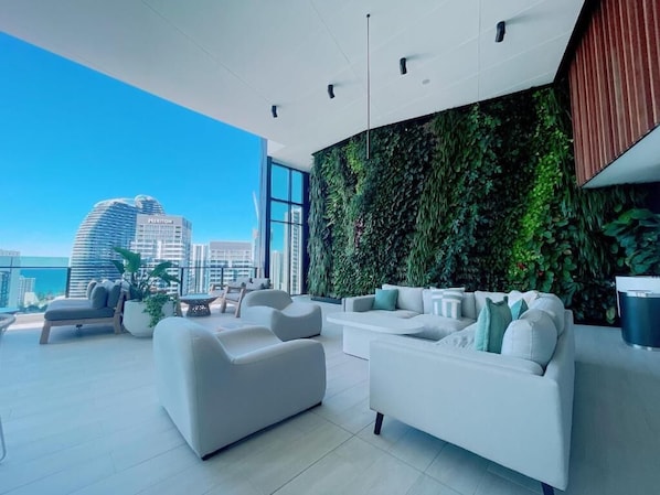 Relax in a spacious living area with a panoramic city view, featuring a curved sofa, armchair, and coffee table.