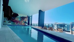 A rooftop pool with lounge chairs and a mural. - Luxurious 1 Bdrm Apartment in GC Casino (Broadbeach)