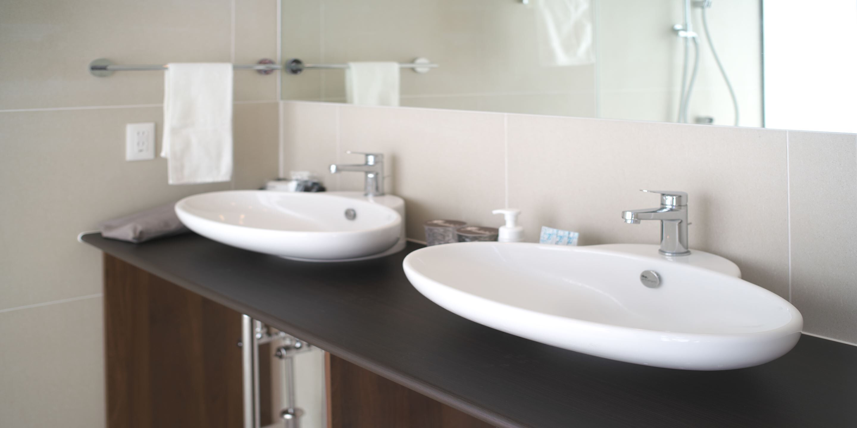 A bathroom with two white sinks, a dark countertop, and a mirror above the sinks.