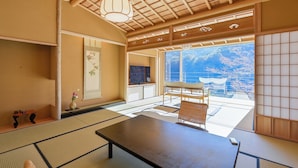A traditional Japanese room with tatami flooring, a low table, and a view of the ocean. - Fukiya Ryokan (Yugawara)