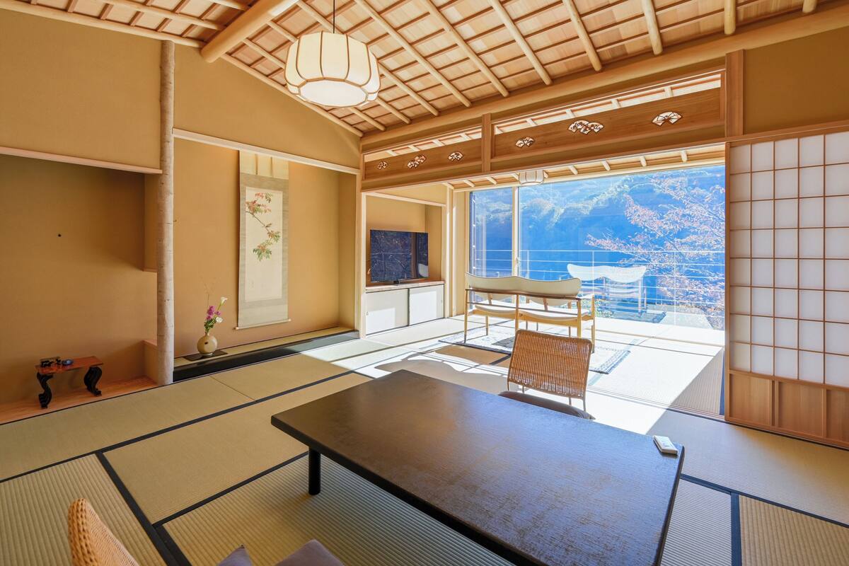 A traditional Japanese room with tatami flooring, a low table, and a view of the ocean.