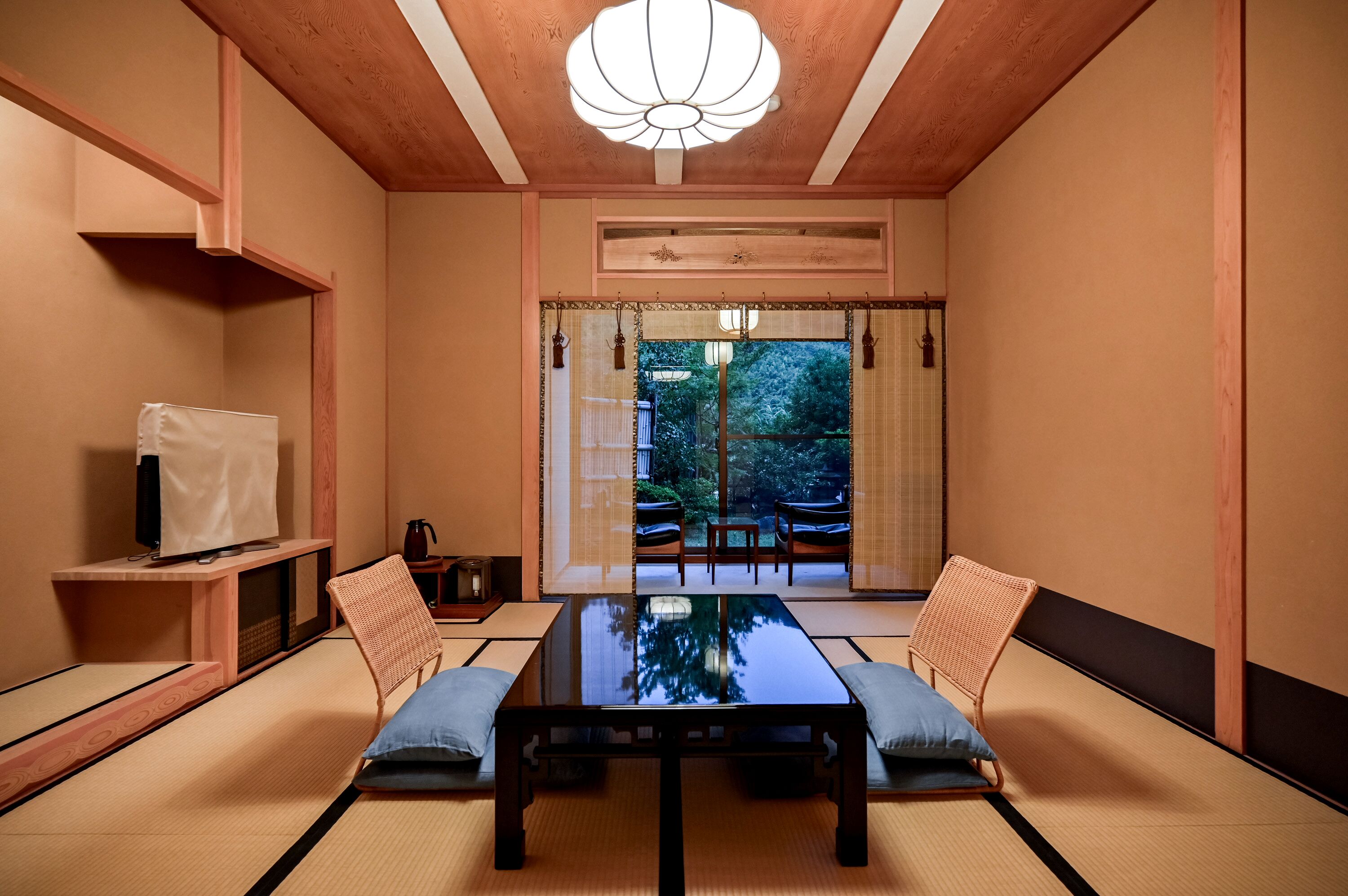 Una habitación japonesa tradicional con suelo de tatami, una mesa baja y vista a un jardín a través de un puertas correderas.