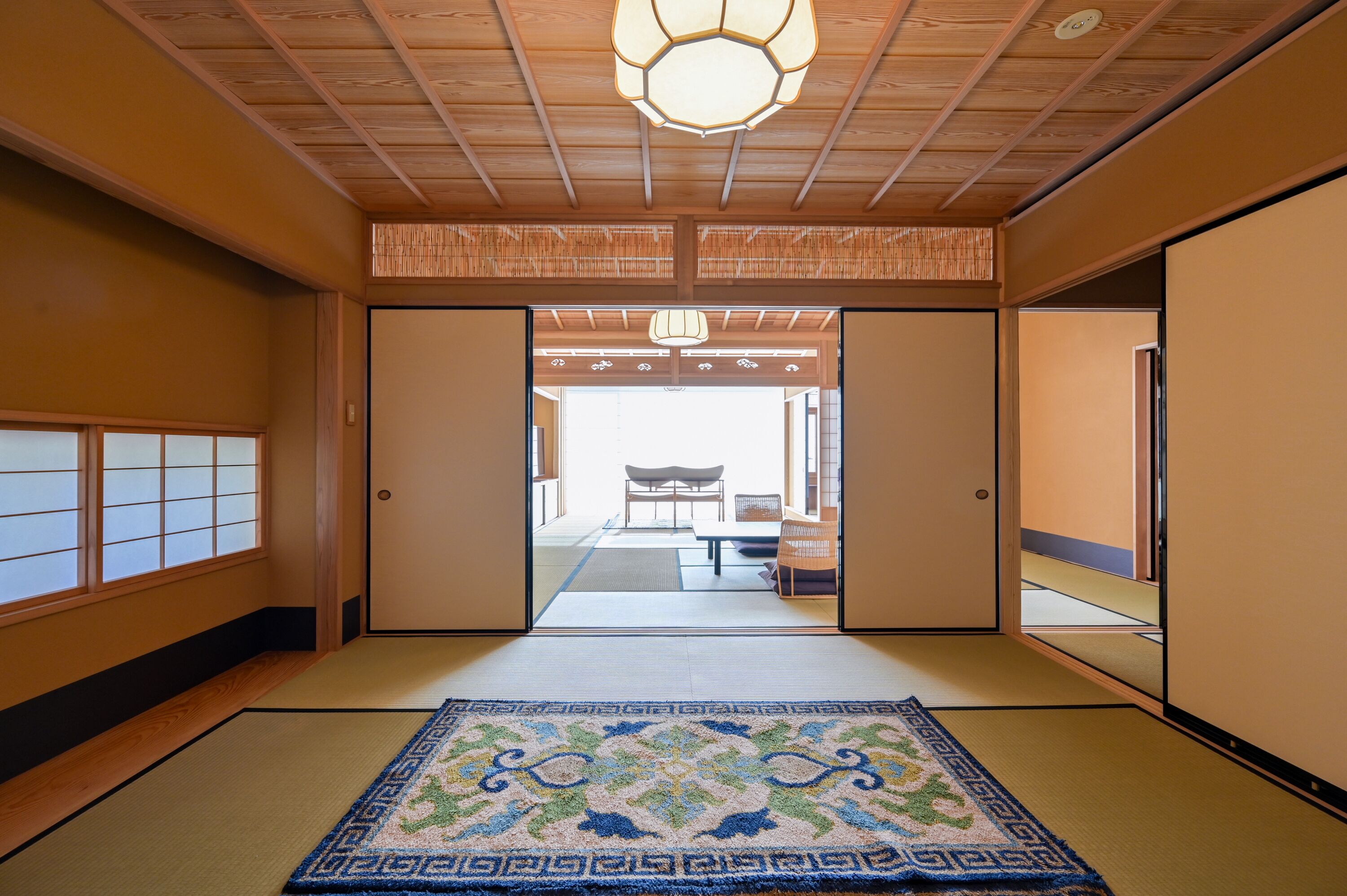 Een traditionele Japanse kamer met tatami vloeren, schuifdeuren en uitzicht op een eetgedeelte.