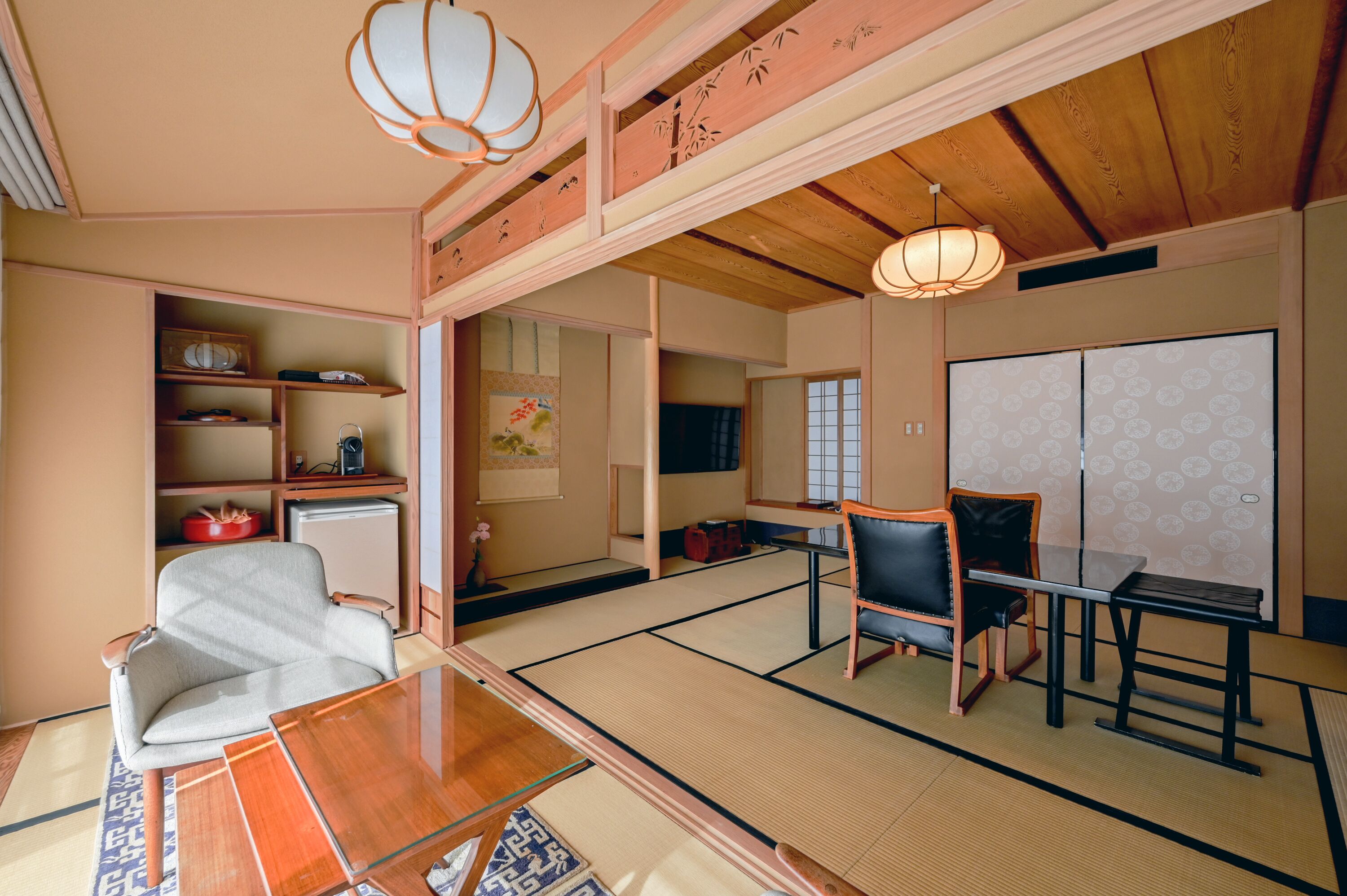 A traditional Japanese room with tatami flooring, a low table, chairs, and a sliding door.