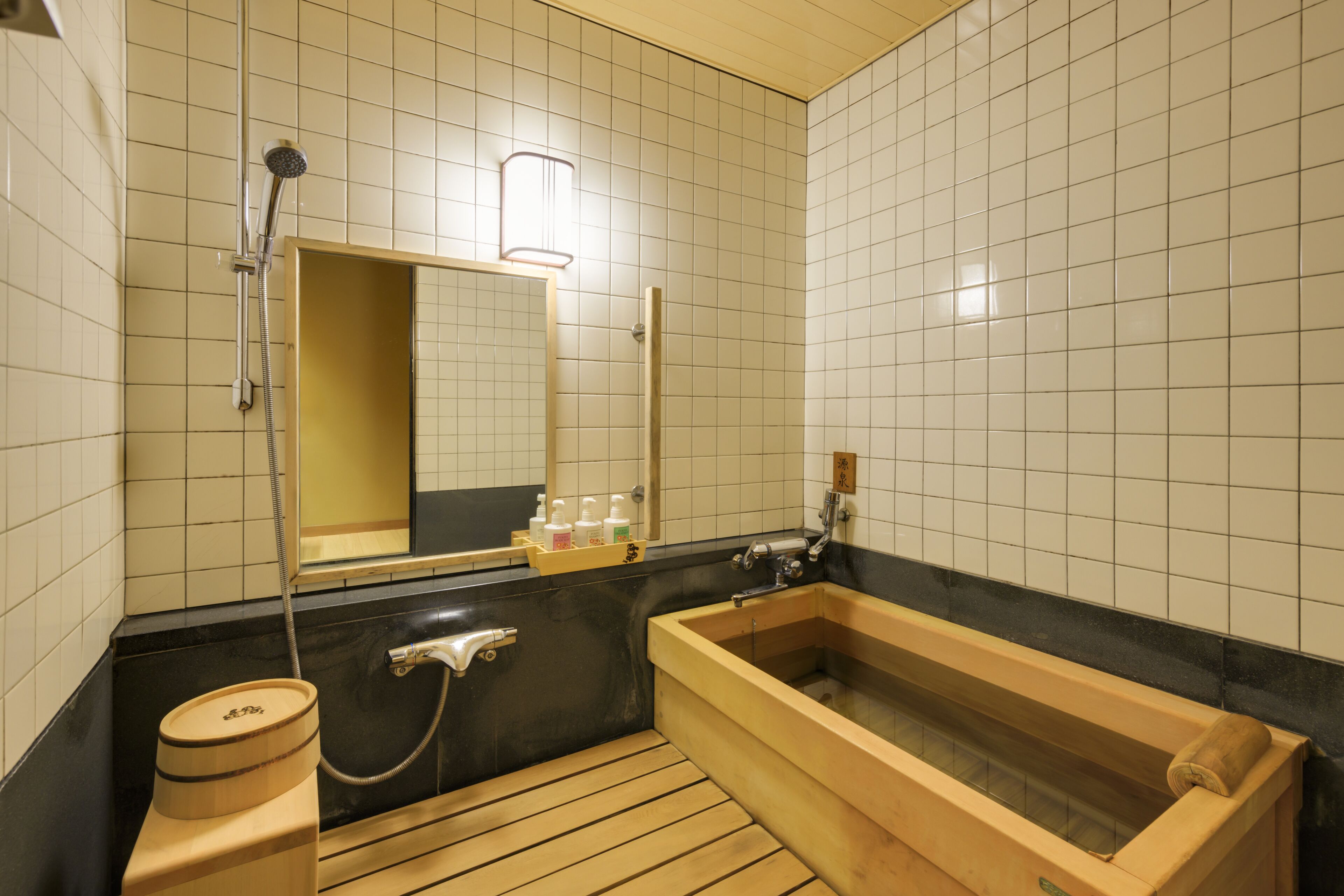 A traditional Japanese-style bathroom with a wooden bathtub, a separate shower area, and a toilet.