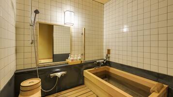 A traditional Japanese-style bathroom with a wooden bathtub, a separate shower area, and a toilet.