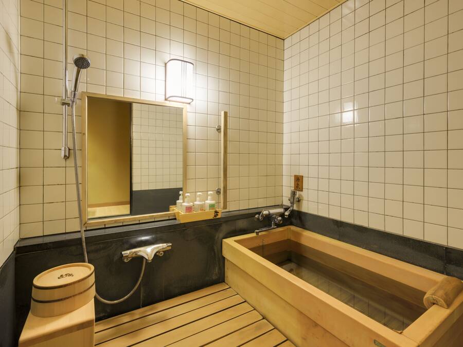 A traditional Japanese-style bathroom with a wooden bathtub, a separate shower area, and a toilet.