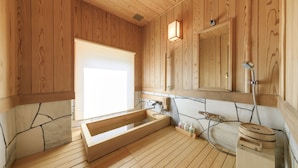 A wooden bathroom with a large bathtub, a sink, and a mirror. - Fukiya Ryokan (Yugawara)