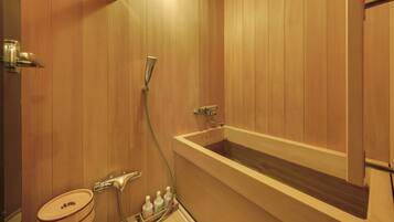 A wooden-paneled bathroom with a bathtub, a toilet, and a shower.