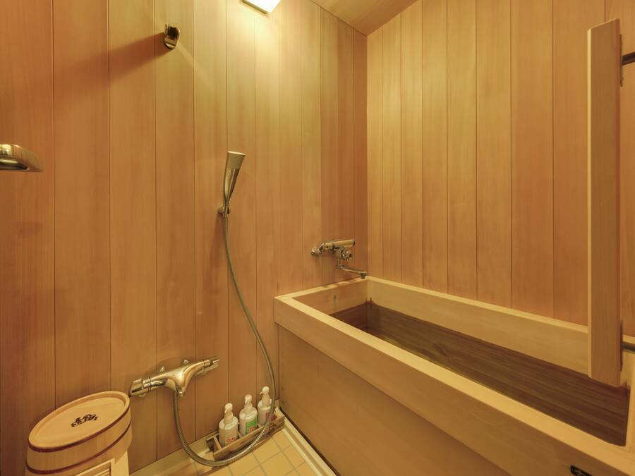 A wooden-paneled bathroom with a bathtub, a toilet, and a shower.