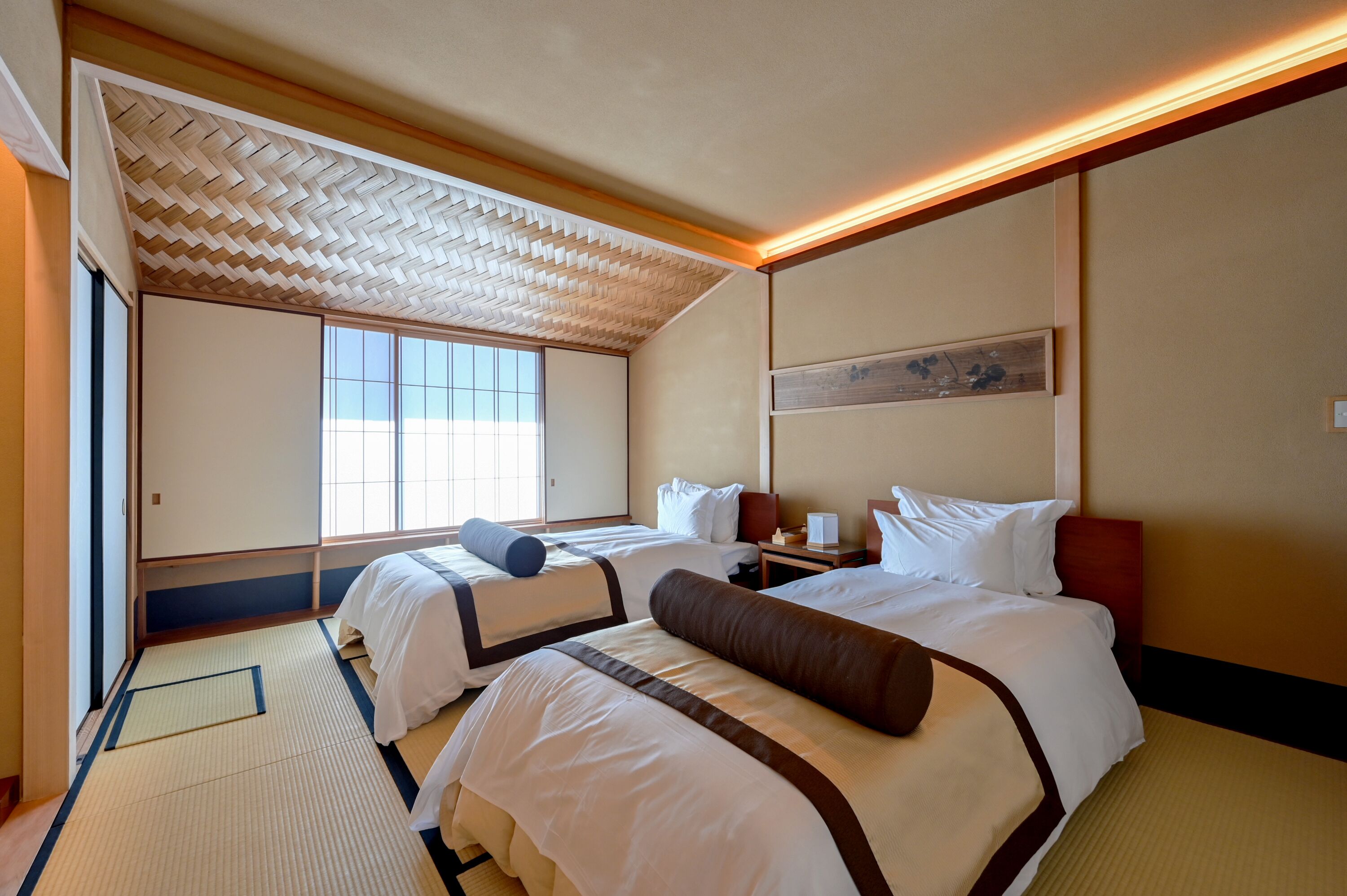 Quarto de hotel com duas camas, uma janela ampla, um design de teto tradicional e um quadro na parede.