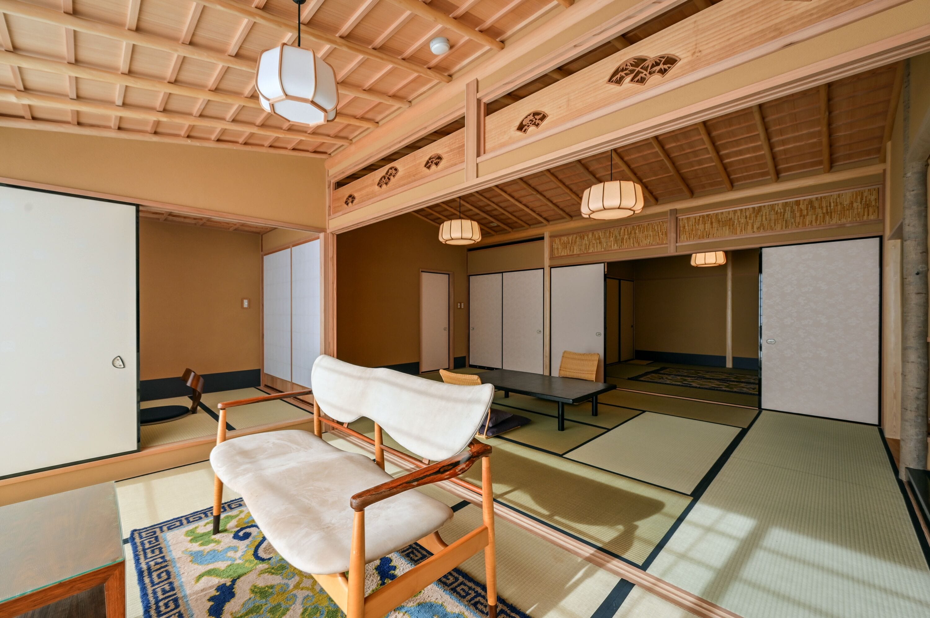 A traditional Japanese room with tatami flooring, a low wooden table, and a white cushioned chair.