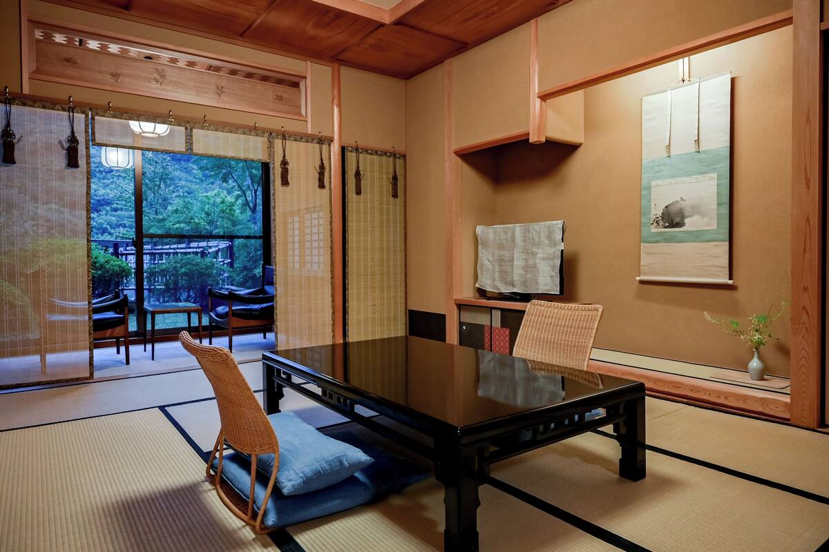 A traditional Japanese-style room with tatami flooring, a low table, and a television.