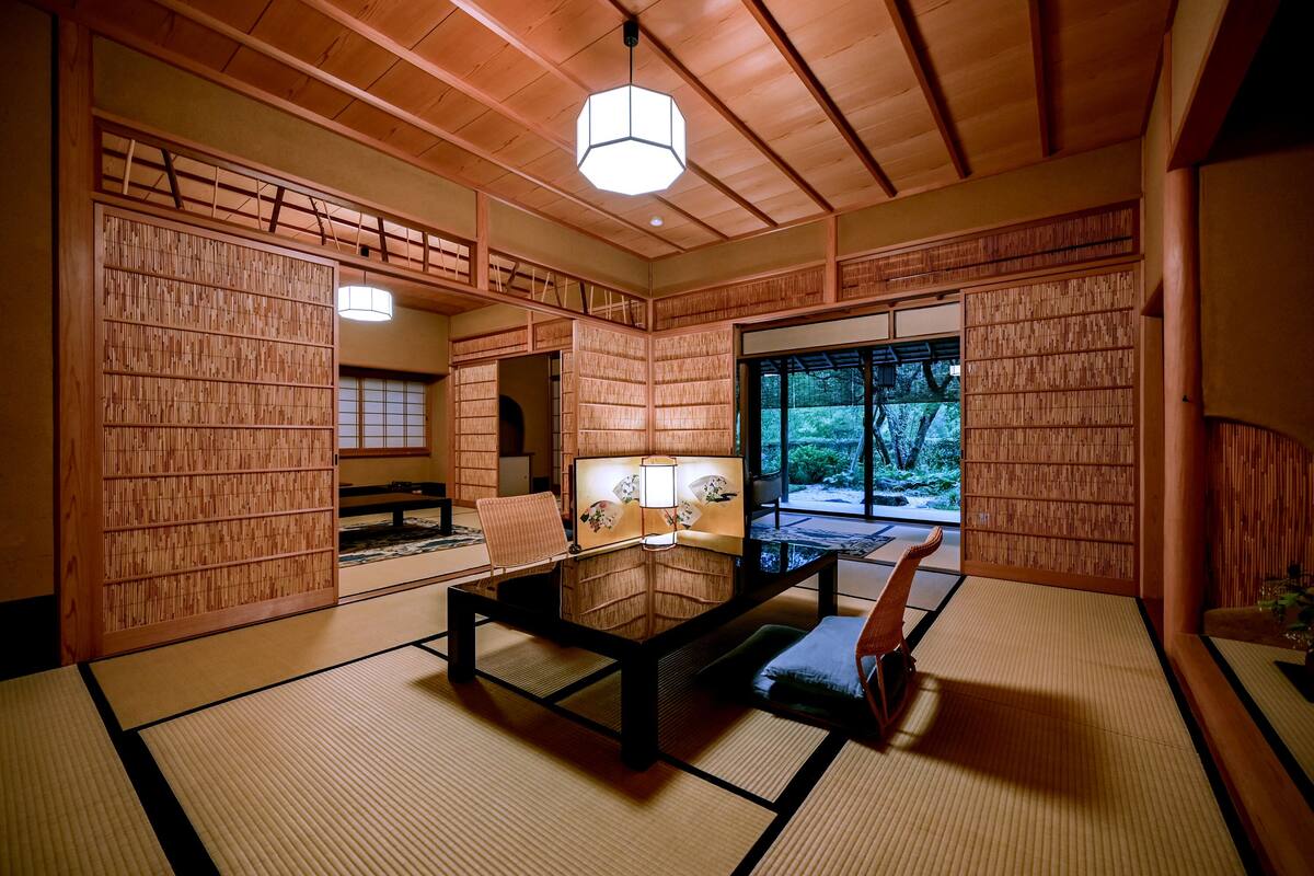 A traditional Japanese room with tatami flooring, a low table with cushions, and sliding doors.