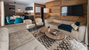 Un salon moderne avec un canapé, des fauteuils, une table basse et un téléviseur.