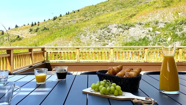 Une table dressée avec des aliments pour le petit-déjeuner et une vue panoramique sur une colline.