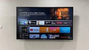 A flat-screen TV mounted on a wall displaying a streaming service interface with various app icons. - Modern 3 Bedroom 2 Bath Home Centrally Located! (Del Rio)