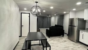 A modern kitchen with a stainless steel refrigerator, a dining table with benches, and a chandelier. - Modern 3 Bedroom 2 Bath Home Centrally Located! (Del Rio)