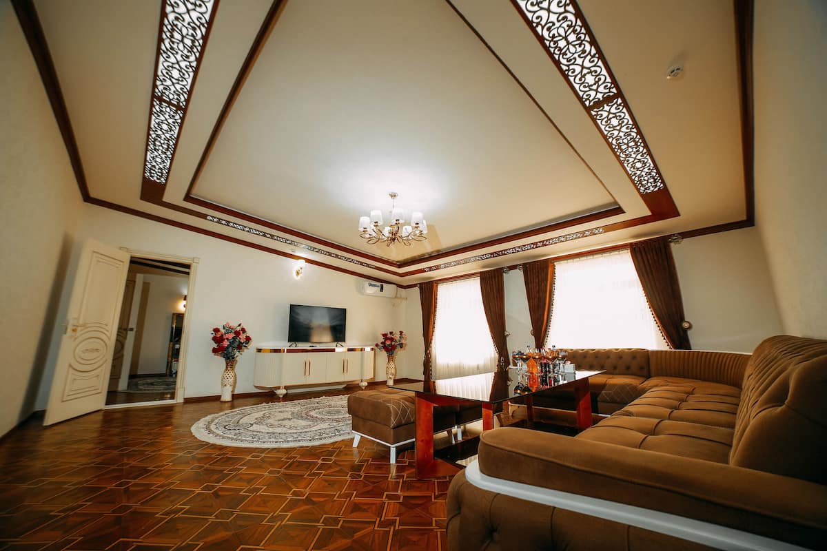 A spacious living room with a large sofa, a television, and a decorative chandelier.