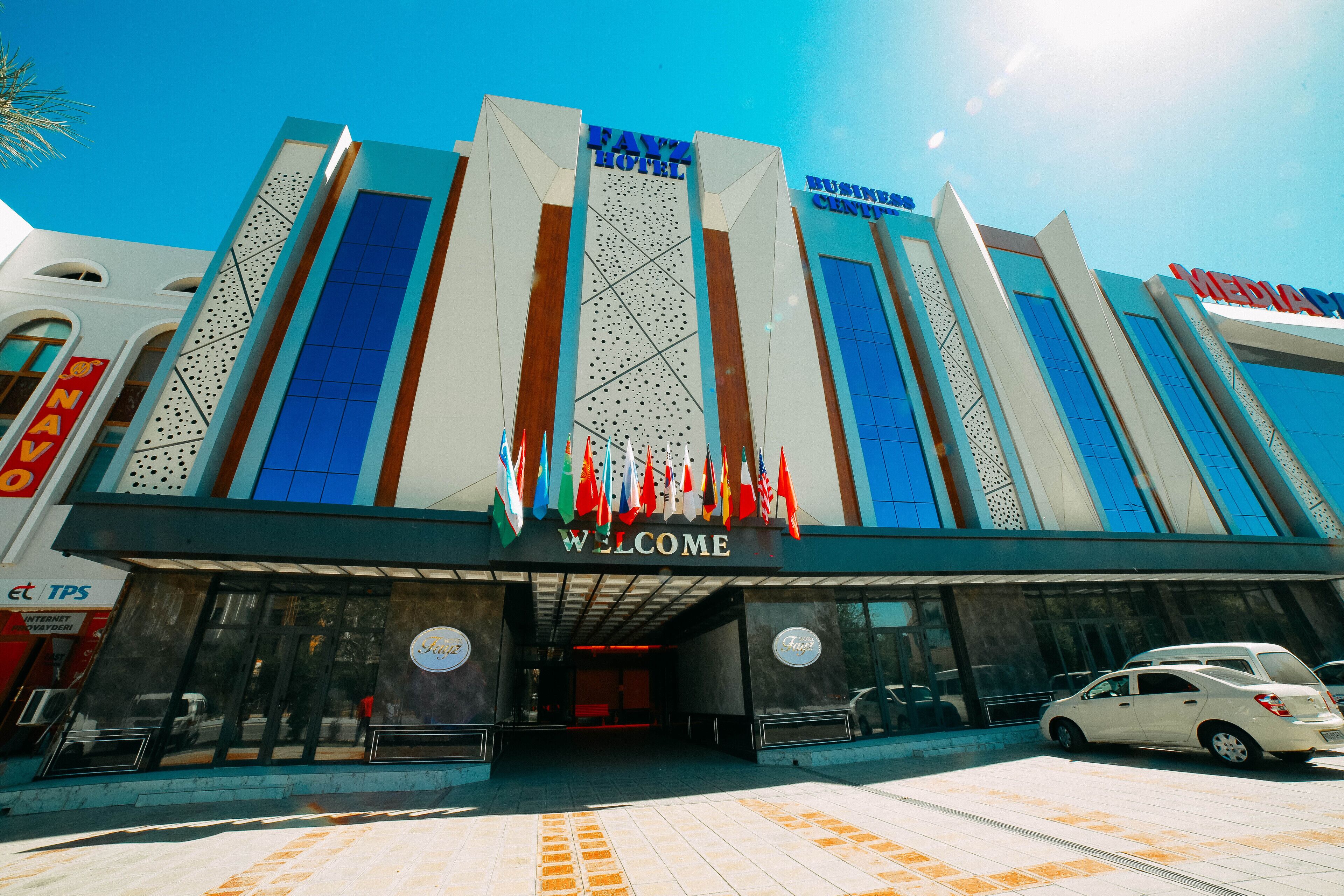Et hotel med en moderne facade, et 'Welcome' skilt og et 'Business Center' skilt.