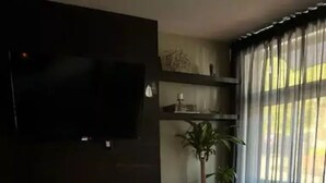 A modern living room with a dark-colored sofa, a glass coffee table, and a fireplace. - Mr. Holmes Retreat (Pittsburgh)