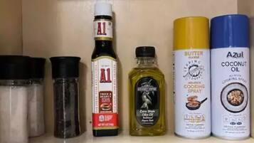 A kitchen shelf with various cooking oils and seasonings.