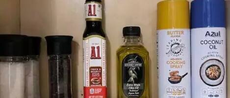A kitchen shelf with various cooking oils and seasonings.