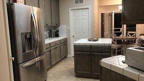 A kitchen with stainless steel appliances, wooden cabinets, and a tiled backsplash.