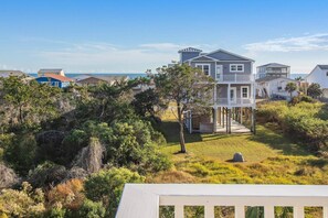 Una casa sul lungomare con un balcone, immersa nel verde e vista mare.