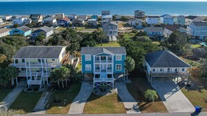 A coastal residential area with multiple two-story houses, some with balconies, and a view of the ocean. - Wonderful Ocean Views - Sleeps 12 -3 Mins to Beach (Oak Island)