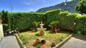 Un jardin agrémenté d’une fontaine, de plantes en pot et offrant une vue dégagée sur une montagne en arrière-plan.