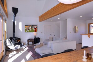 A living room with a fireplace, a sofa, a television, and a wooden ceiling.