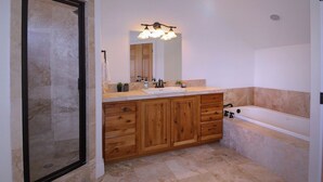 Une salle de bain avec un meuble-lavabo en bois, un évier, un miroir, une douche et une baignoire.