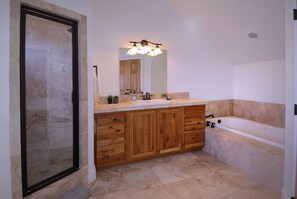 A bathroom with a wooden vanity, a sink, a mirror, a shower, and a bathtub.