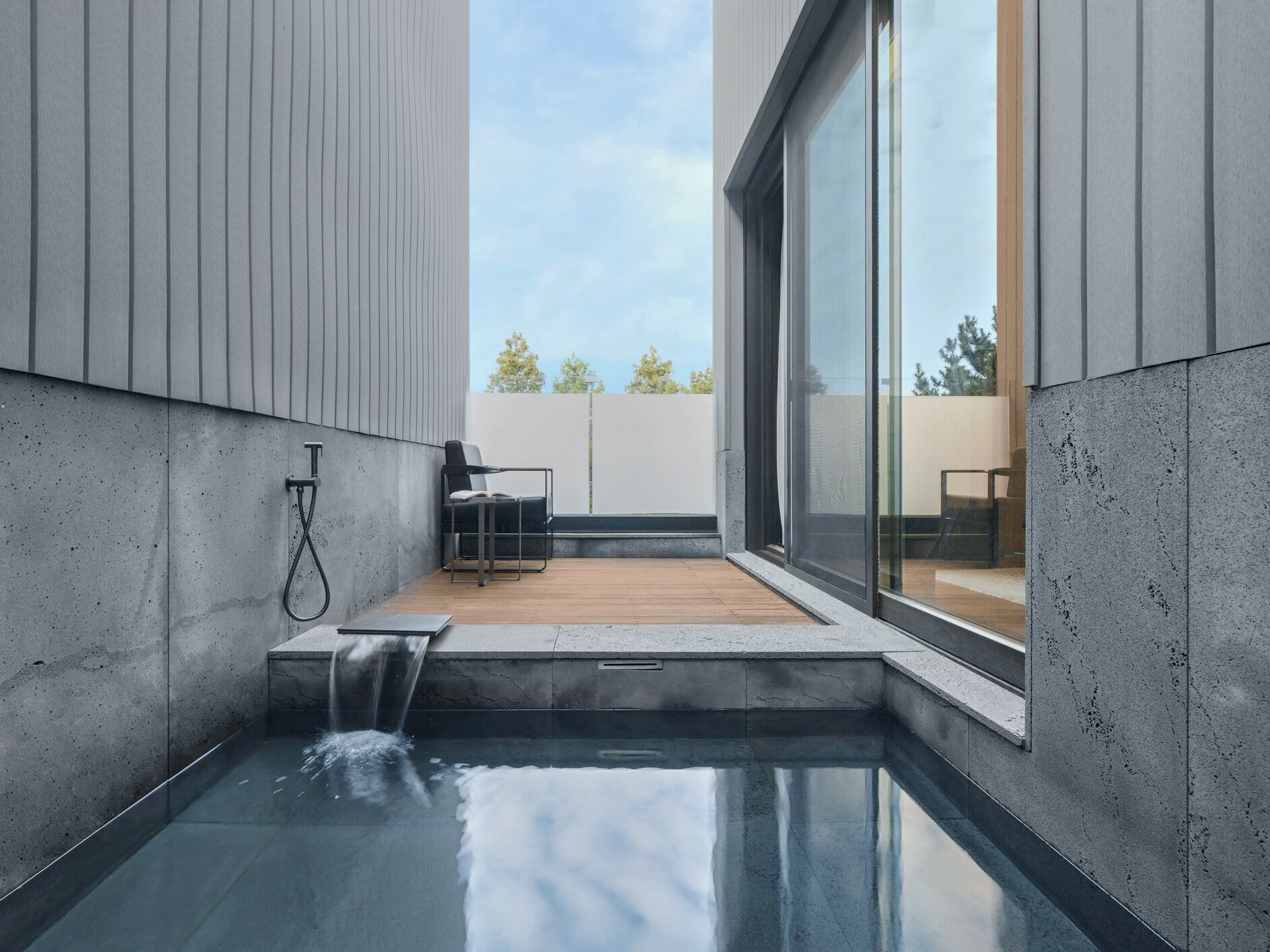 A modern outdoor pool area with a minimalist design, a seating area, and a glass enclosure.