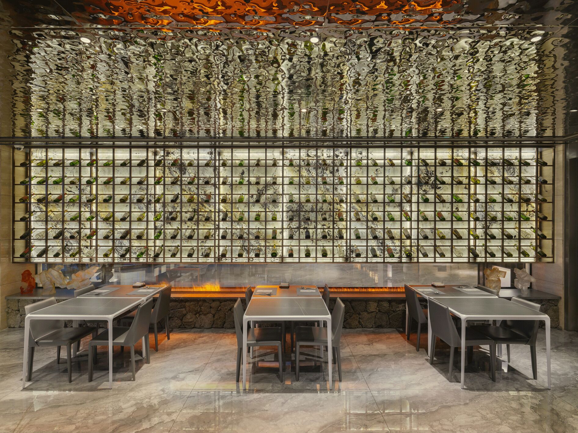A restaurant with a wall of wine bottles, tables, and chairs.