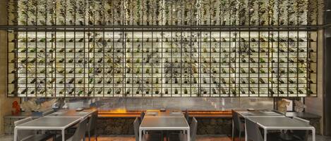 A restaurant with a wall of wine bottles, tables, and chairs.