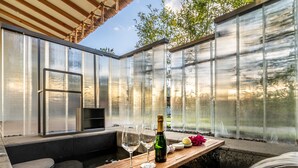 Un área de hidromasaje con terraza de madera, una botella de champán y copas.