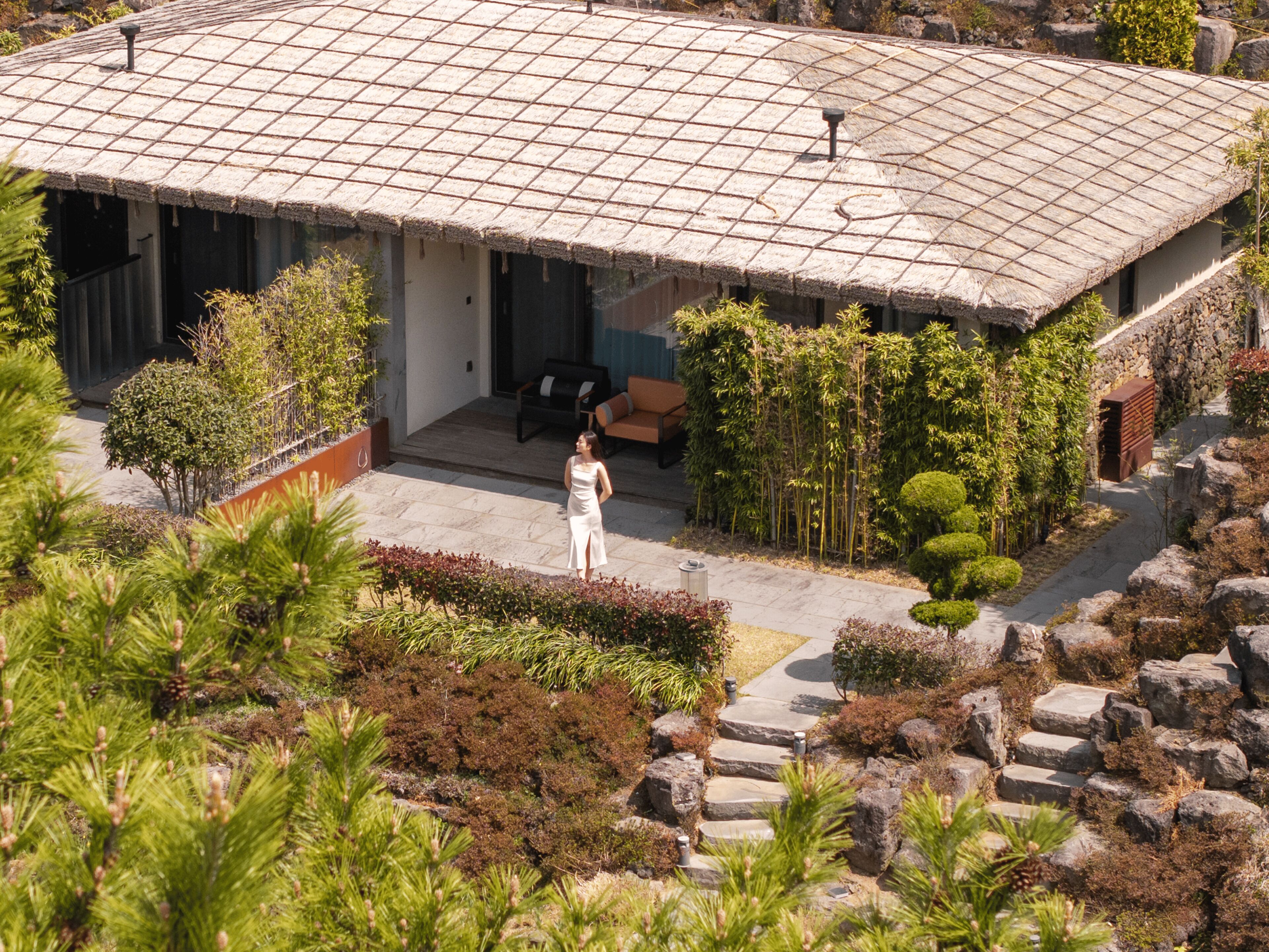 A house with a tiled roof, a covered porch, and a landscaped garden with various plants and shrubs.