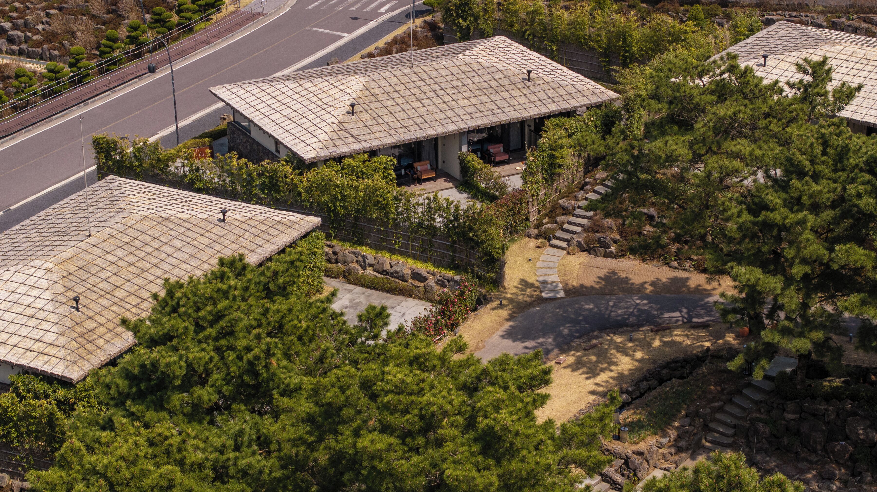 A building with a tiled roof, surrounded by trees and a stone pathway.