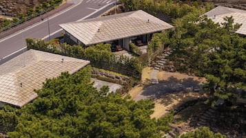A building with a tiled roof, surrounded by trees and a stone pathway.