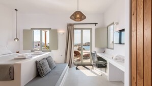 Et moderne soveværelse med seng, siddeplads, skrivebord og et stort vindue med havudsigt.