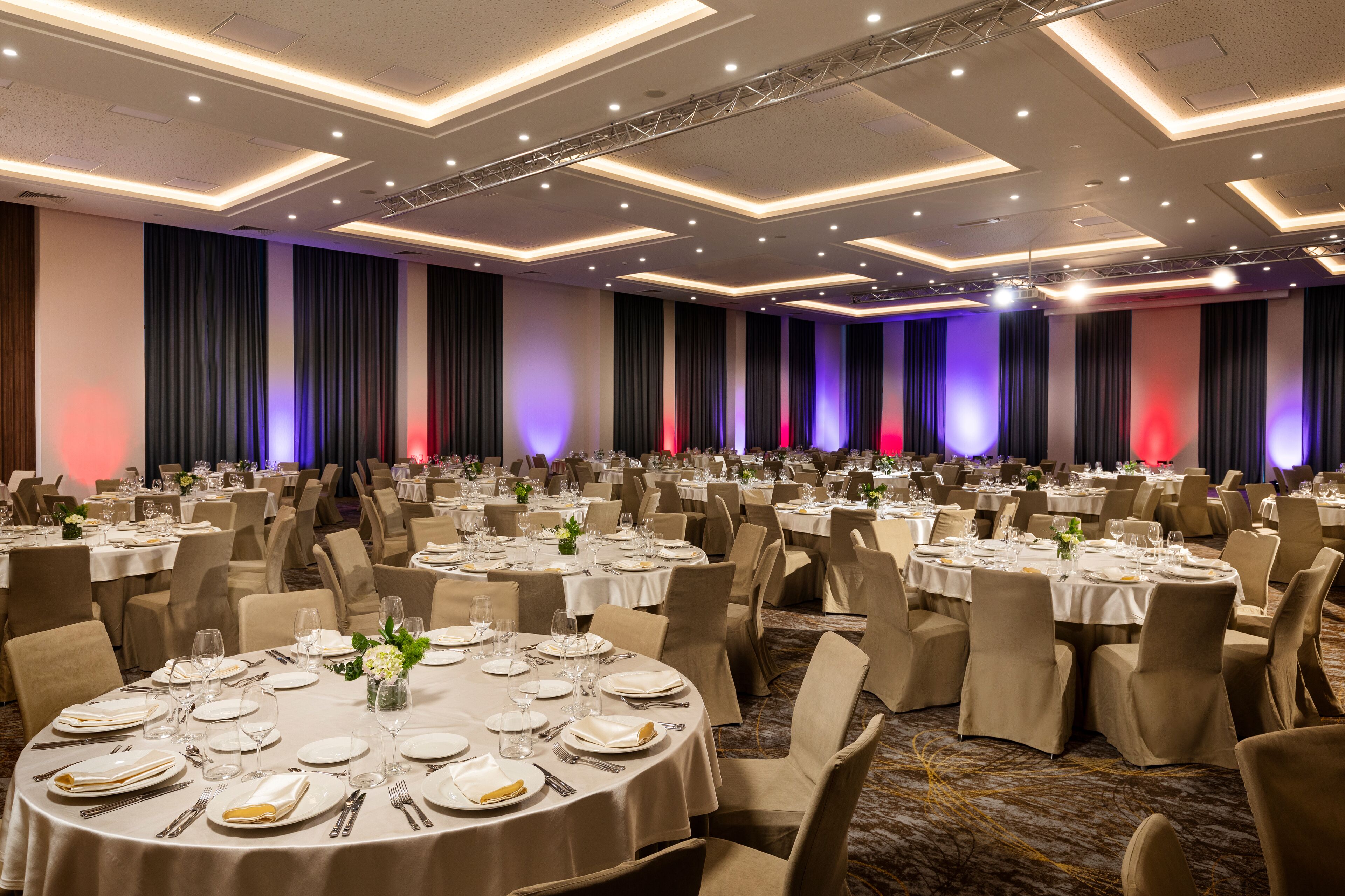Un salón de banquetes con mesas redondas dispuestas para comer, equipado con sillas y vajilla.