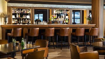 Una zona de bar con varios taburetes, una barra y una variedad de botellas.
