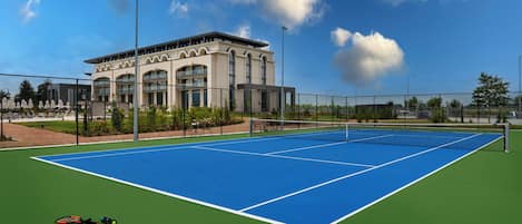 A tennis court with a net, a building in the background, and a clear sky.