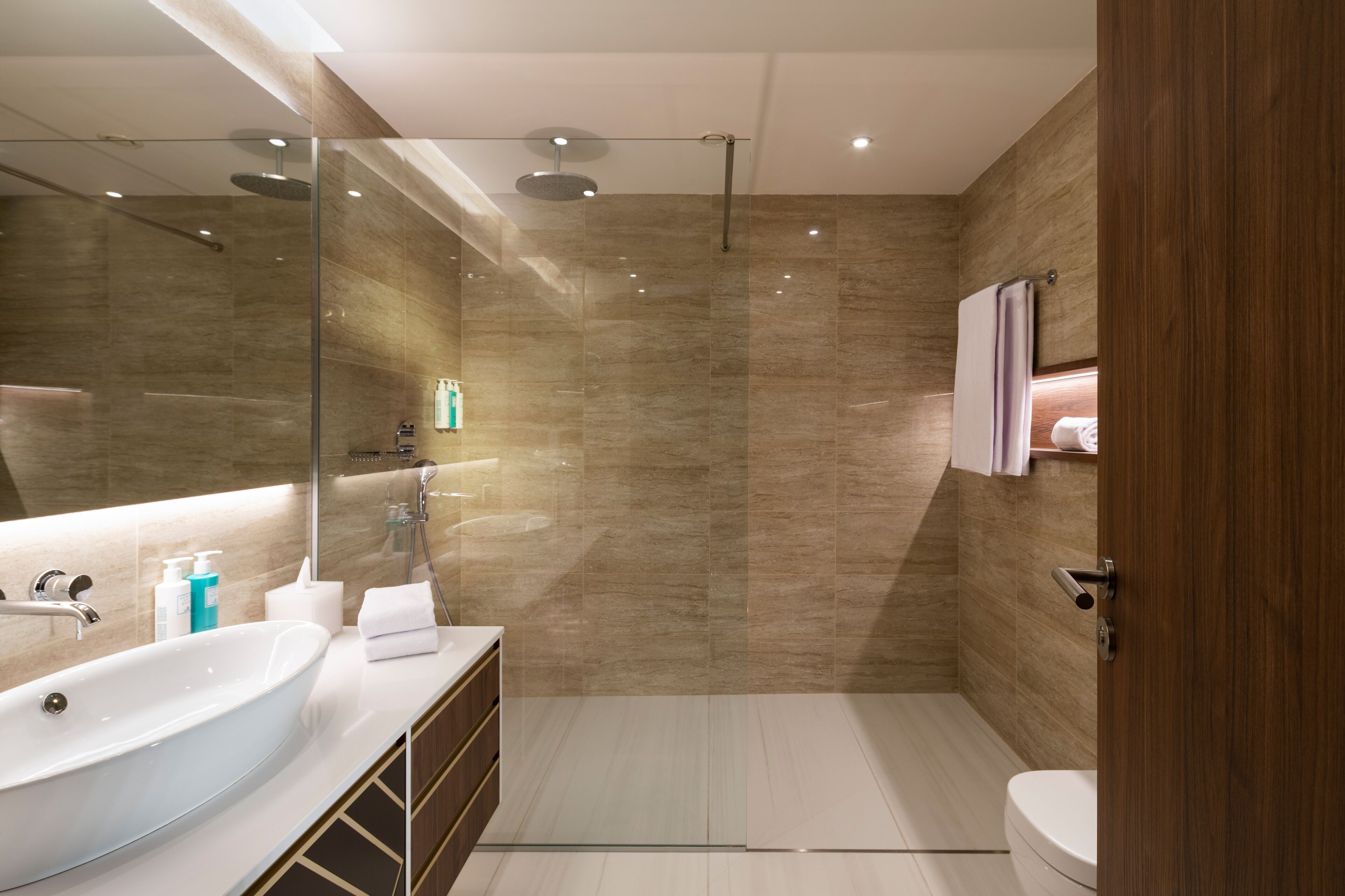 A modern bathroom with a large sink, mirror, and shower.